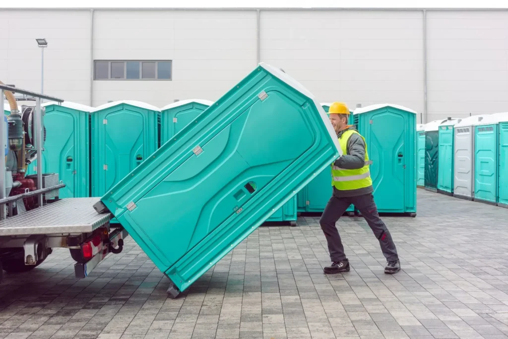 A man organizes and loads portable toilets in a warehouse for efficient portable toilet rental.