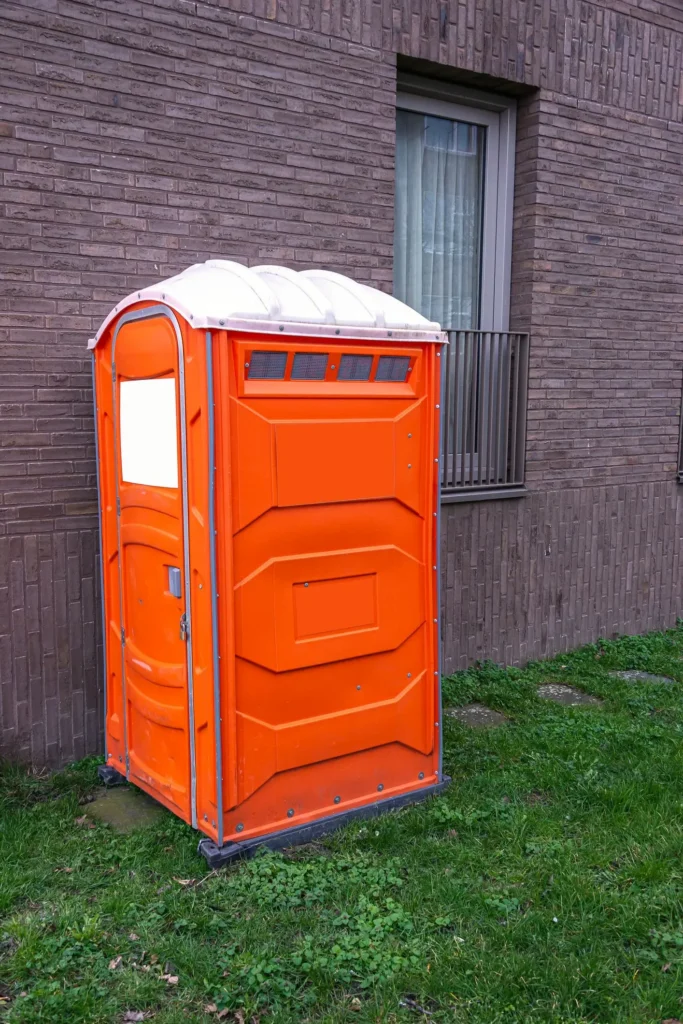 Mobile outdoor toilet cabin placed on grass near an apartment for portable toilet rental service. Mobile outdoor toilet cabin placed on grass near an apartment for portable toilet rental service.