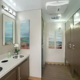 Spacious portable restroom trailer with mirror, sinks, and various stalls.