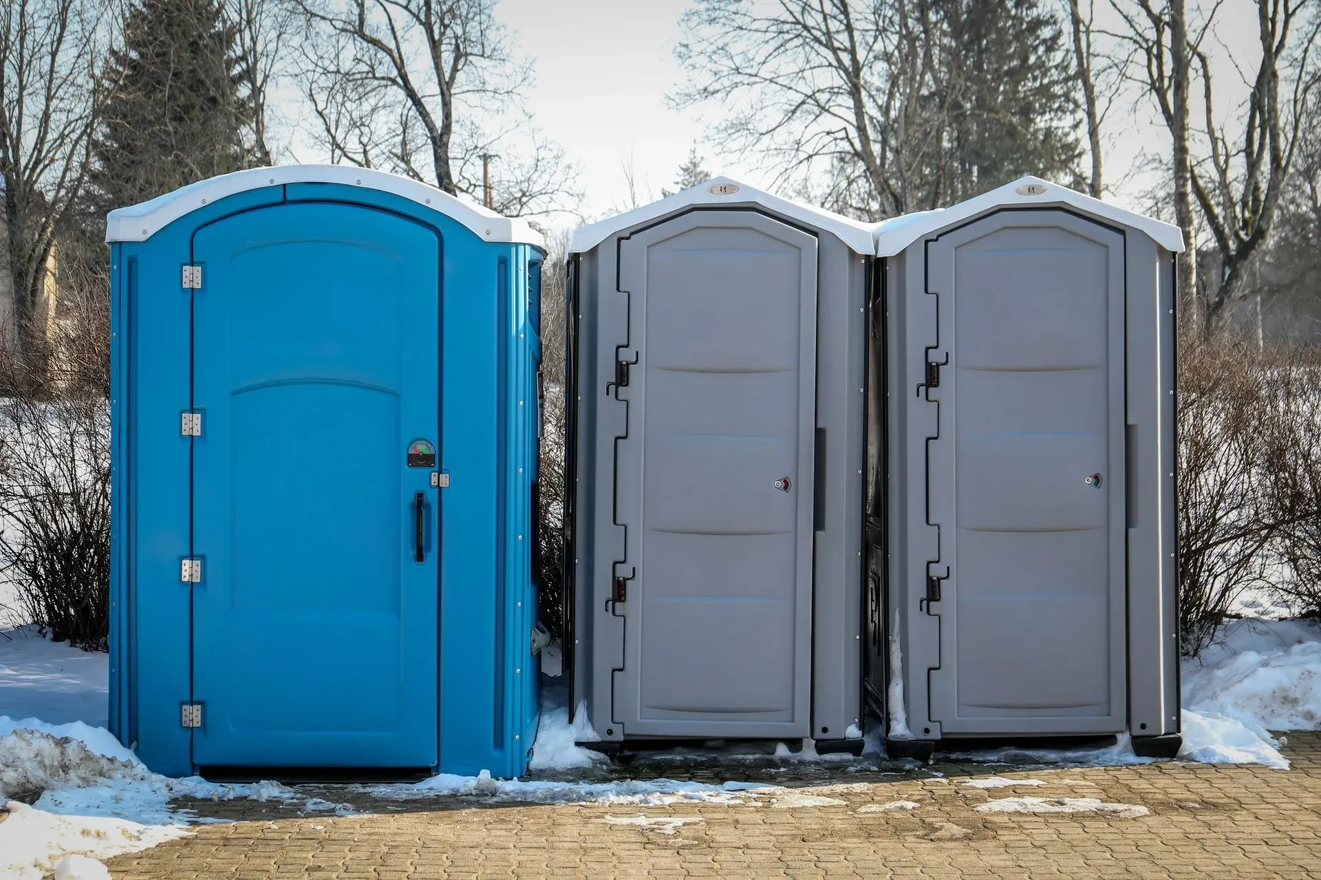 Portable toilets in a snowy outdoor setting.